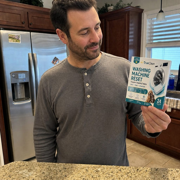 Customer in kitchen holding TrueClean washer reset box